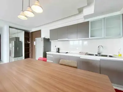 a kitchen with a wooden table and a kitchen with white cabinets at Regalia by sweet home in Kuala Lumpur