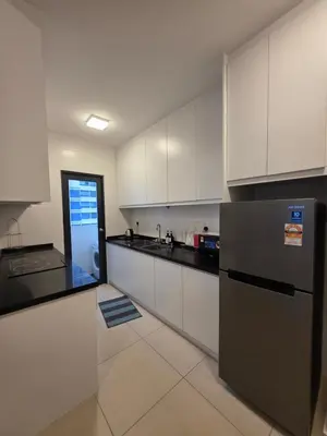 a kitchen with white cabinets and a stainless steel refrigerator at Reizz Residence by Perkasa Suites in Batu Empat