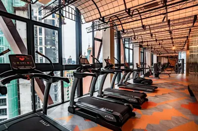 a row of treadmills in a gym with large windows at Scarletz Suites KLCC by Minshuku in Kuala Lumpur