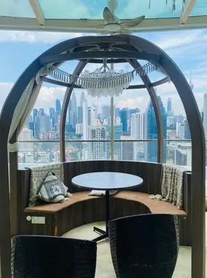 a table and chairs in a room with a view of a city at Regalia KLCC View by Ucare Suites in Kuala Lumpur