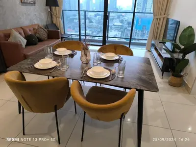 a dining room table and chairs with plates and glasses at Trion by sweet home in Kuala Lumpur