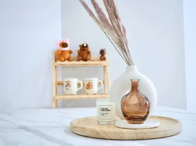 a table with a vase and a candle on a cutting board at Capybara Trion KL View in Kuala Lumpur