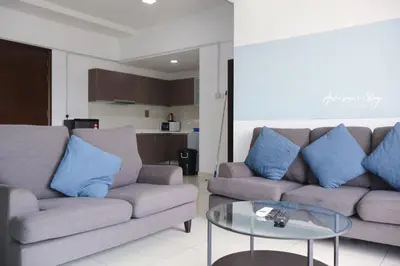 a living room with two couches and a glass table at NJ Homestay Hostel at Regalia Residence in Kuala Lumpur