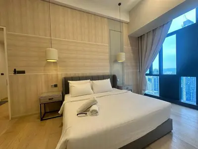 a bedroom with a large white bed and a large window at Holiday Suites at Star in Kuala Lumpur