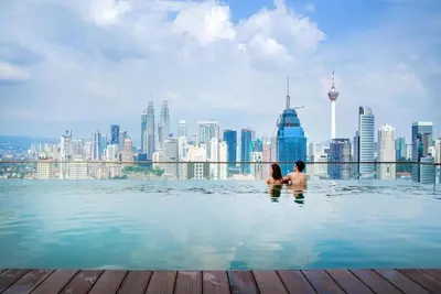 a couple sitting in a infinity pool with a city skyline at 2br 2ba in the heart of KL, Regalia Residence in Kuala Lumpur