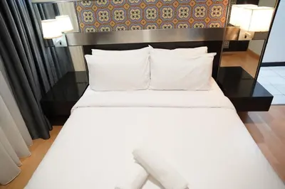 a bed with white sheets and pillows in a room at The Luxe Apartment 2 Bedrooms in Kuala Lumpur