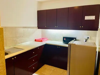 a kitchen with brown cabinets and a refrigerator at Jalan imbi Suites At Times Square KL in Kuala Lumpur