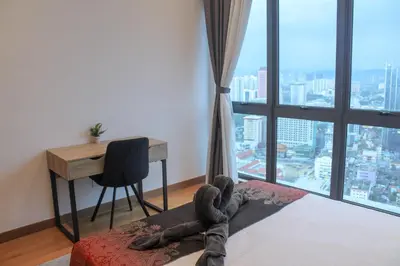 a person laying on a bed in a room with a desk at Alaman Luxe suites KLCC in Kuala Lumpur