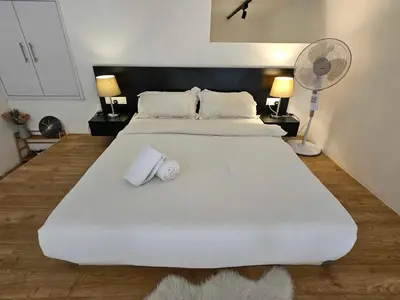 a large white bed with two pillows and a fan at Scenic Garden Balcony EST Bangsar Studio for 2 in Kuala Lumpur