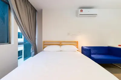 a bedroom with a white bed and a blue chair at Upstairs Downstairs CoLiving Kampung Pandan in Kuala Lumpur