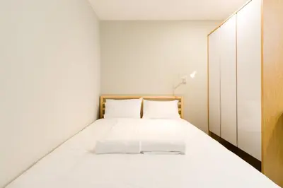 a bedroom with a white bed and a wooden cabinet at Upstairs Downstairs CoLiving Kampung Pandan in Kuala Lumpur