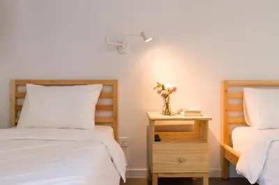 a bedroom with two beds and a table with a vase of flowers at Upstairs Downstairs CoLiving Kampung Pandan in Kuala Lumpur
