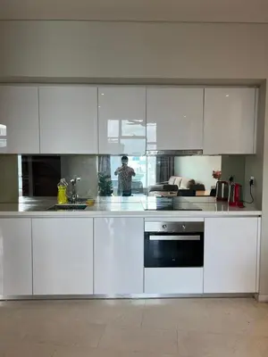 a kitchen with white cabinets and a person standing in it at Sky Suites KLCC by ARBA in Kuala Lumpur
