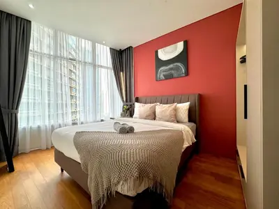 a bedroom with a red wall with a bed and a window at Sky Suites Lovely 3BR Suite at KLCC in Kuala Lumpur
