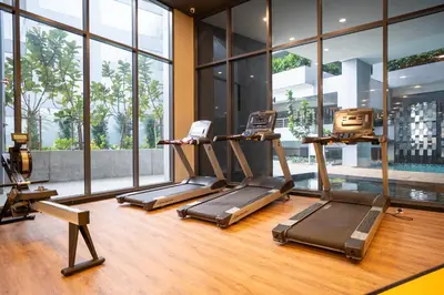 a gym with three treadmills in a room with windows at Neu Suites By Cozy Unit L20RA near KLCC & Jelatek LRT in Kuala Lumpur