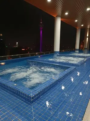 a large swimming pool with a tower in the background at LUX 39A Balcony KLCC View 1 Bedroom Infinity Pool in Kuala Lumpur