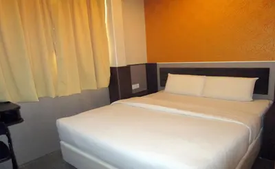 a white bed in a room with a window at T-Hotel Bukit Bintang in Kuala Lumpur