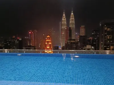a swimming pool with a view of the city at night at COL 93B Balcony KLCC View & Infinity Pool Studio in Kuala Lumpur