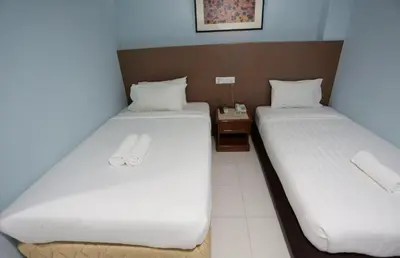 two twin beds in a room with a night stand at Hotel La ISRA at Bukit Bintang in Kuala Lumpur