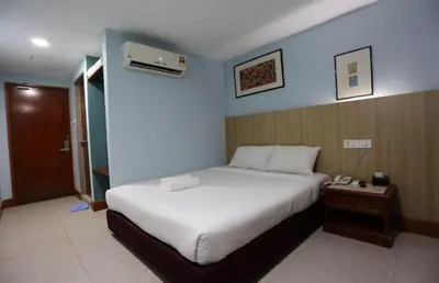 a hotel room with a bed and a night stand with a phone at Hotel La ISRA at Bukit Bintang in Kuala Lumpur