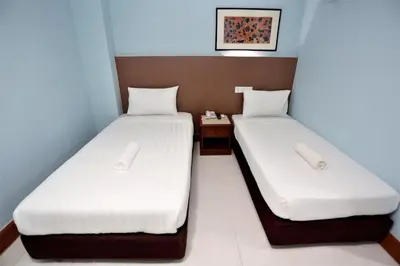 two beds in a small room with white sheets at Hotel La ISRA at Bukit Bintang in Kuala Lumpur