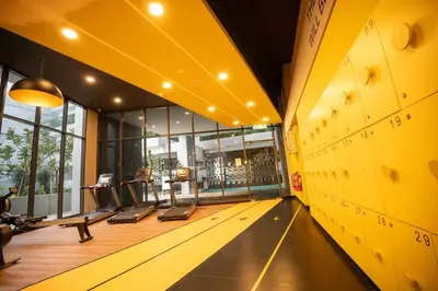 an empty gym with a yellow wall and treadmills at Neu Suites By Cozy Unit L20RB near KLCC & Jelatek LRT in Kuala Lumpur