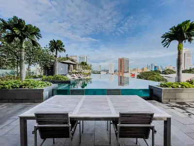 a table and chairs on the roof of a building with a pool at Opus Residences by Wakely Kuala Lumpur in Kuala Lumpur