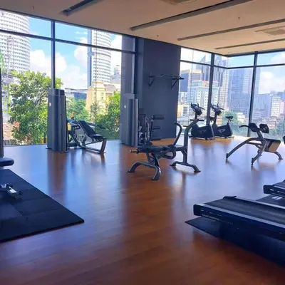 a gym with treadmills and exercise bikes in a room with windows at 2-Bedroom Apartment in Kuala Lumpur City Center in Kuala Lumpur