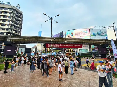 a crowd of people crossing a street in a city at The Mews Kuala Lumpur Homestay with Bathtub 700m to KLCC by Cloud Host in Kuala Lumpur
