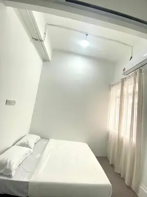 a white room with a bed and a window at Bright Star Inn in Kuala Lumpur