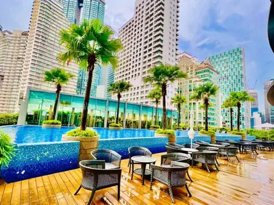 a hotel patio with tables and chairs and palm trees at KLCC Vortex Suites Residence in Kuala Lumpur