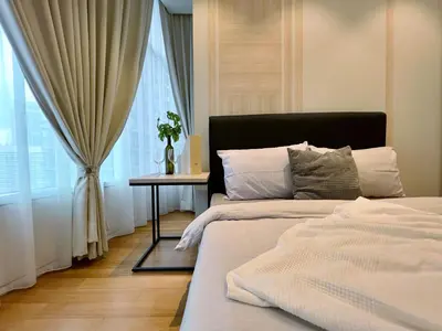 a bedroom with two beds and a table and a window at Sky Suites Centrale 3BR Suite at KLCC in Kuala Lumpur