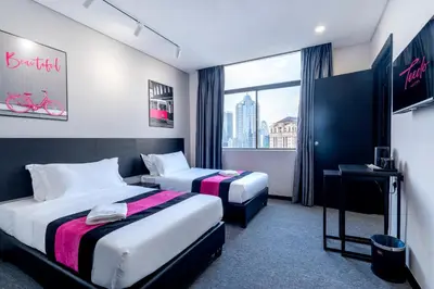 a hotel room with two beds and a window at TEEDO Hotel Kuala Lumpur in Kuala Lumpur