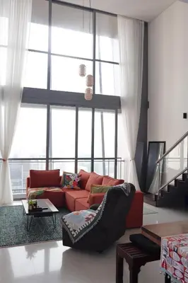 a living room with a red couch in front of a large window at The Bohomes with KLCC view in Kuala Lumpur