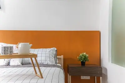 a bedroom with a bed with a wooden headboard and a table at Relaxing Muji Retreat with Jacuzzi, Retro Games, MRT in Kuala Lumpur