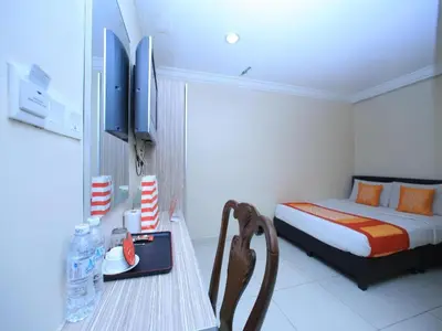 a bedroom with a bed and a table with a chair at OYO 115 Hotel Safari 1 in Kuala Lumpur