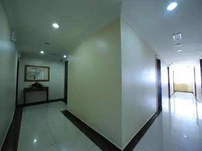 a hallway with white walls and a white tile floor at OYO 115 Hotel Safari 1 in Kuala Lumpur