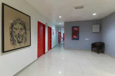 a hallway with red doors and a painting on the wall at OYO 304 Zero Hour Hotel in Kuala Lumpur