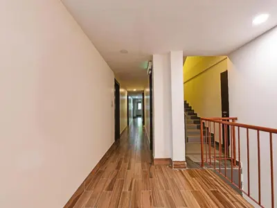 a hallway with white walls and wooden floors and stairs at Capital O 90574 Hotel Glo in Kuala Lumpur
