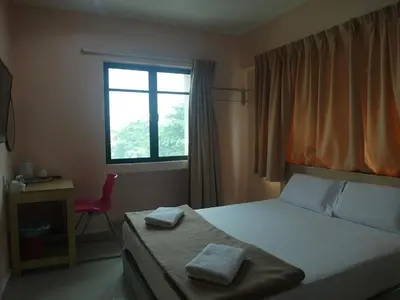 a bedroom with a bed and a red chair and a window at Budget Star Hotel in Kuala Lumpur