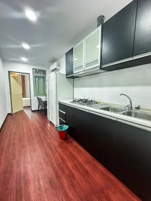 a kitchen with black cabinets and a wooden floor at Taragon Bukit Bintang City Centre in Kuala Lumpur