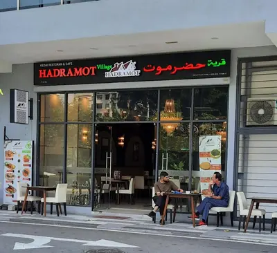 two men sitting at tables in front of a restaurant at Neu Suites By Cozy Unit L30RB 2PAX near KLCC & Jelatek LRT in Kuala Lumpur