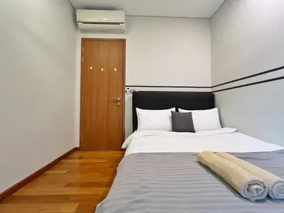 a bedroom with a large bed and a wooden door at Sky Suites Modern 3BR Family Suite at KLCC in Kuala Lumpur
