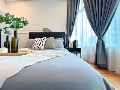 a bedroom with a large bed with blue curtains at Sky Suites Modern 3BR Family Suite at KLCC in Kuala Lumpur
