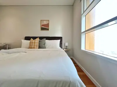 a bedroom with a large white bed and a window at Sky Suites Unique 3BR Suite KLCC View in Kuala Lumpur