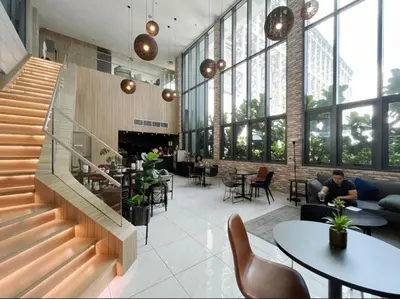 a lobby with a staircase and tables and chairs at KIcc view residences by the colony in Kuala Lumpur