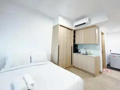 a bedroom with a white bed and a kitchen at The Colony Infinitum By Happy Stay in Kuala Lumpur