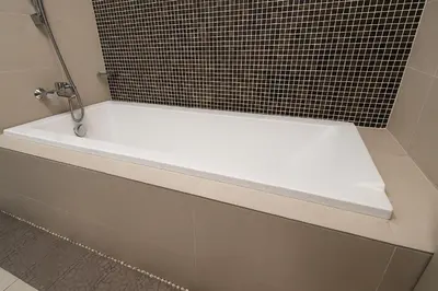 a white bath tub in a bathroom with black tiles at Elegant 1BR in OOAK Suites, Mont Kiara KL - Walk to Malls & Dining in Kuala Lumpur