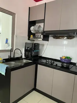 a kitchen with white cabinets and a black counter top at Azmaya homestay in Kuala Lumpur
