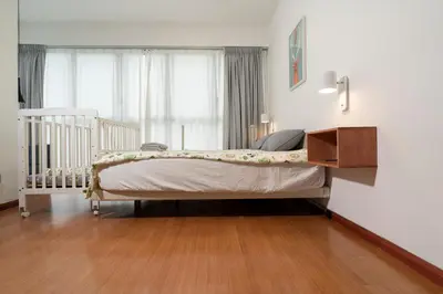 a bed in a bedroom with a crib and a window at Spacious Family Apt 3-Min Walk to KLCC MRT RO Water Baby Crib Home Cinema Projector in Kuala Lumpur